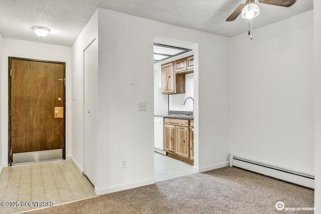 interior space with baseboard heating, a sink, a textured ceiling, baseboards, and light colored carpet