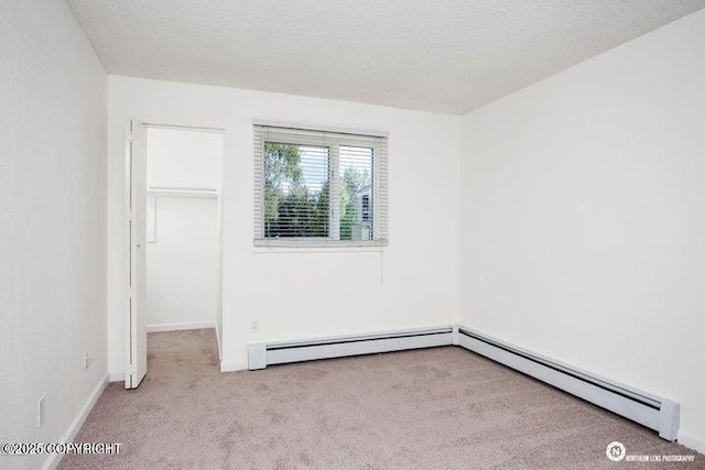 unfurnished room featuring a baseboard radiator, baseboards, a textured ceiling, and carpet flooring