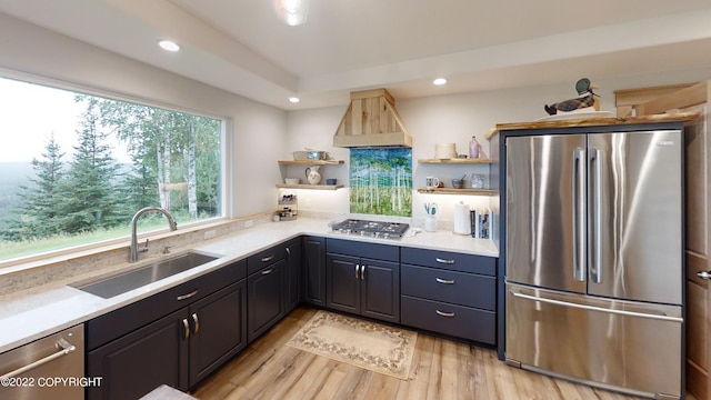 kitchen featuring open shelves, custom exhaust hood, a sink, stainless steel appliances, and light wood-type flooring