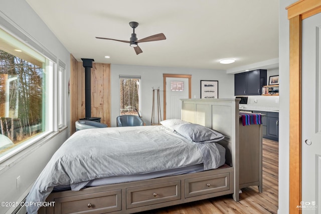 bedroom featuring light wood-style flooring and a wood stove