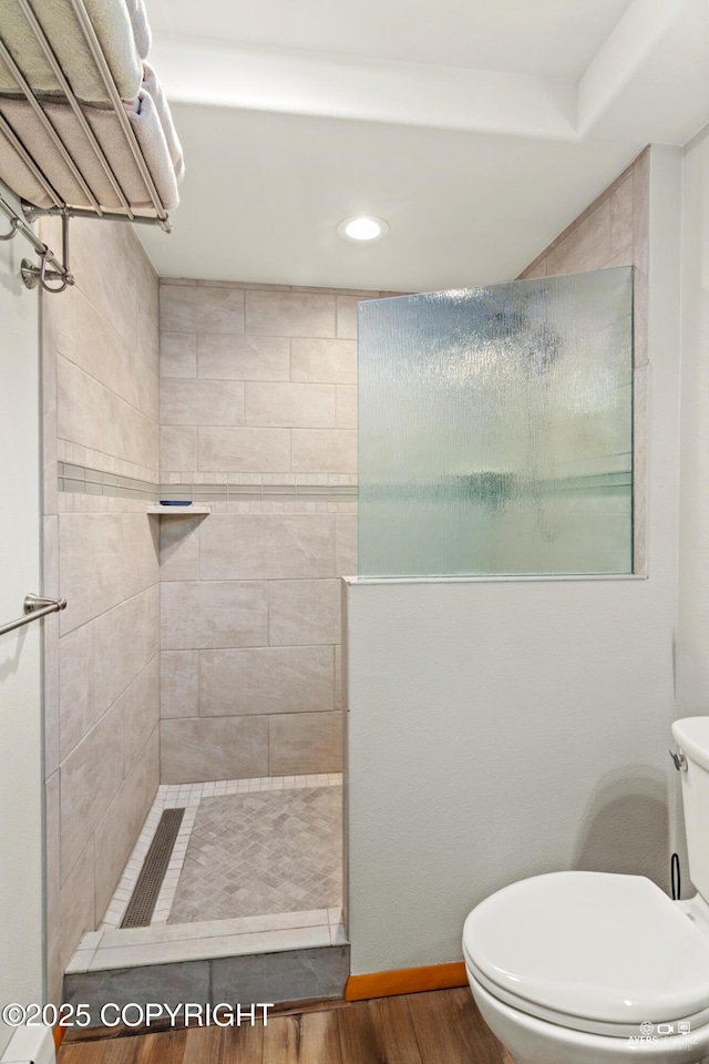 bathroom with a walk in shower, toilet, baseboards, and wood finished floors