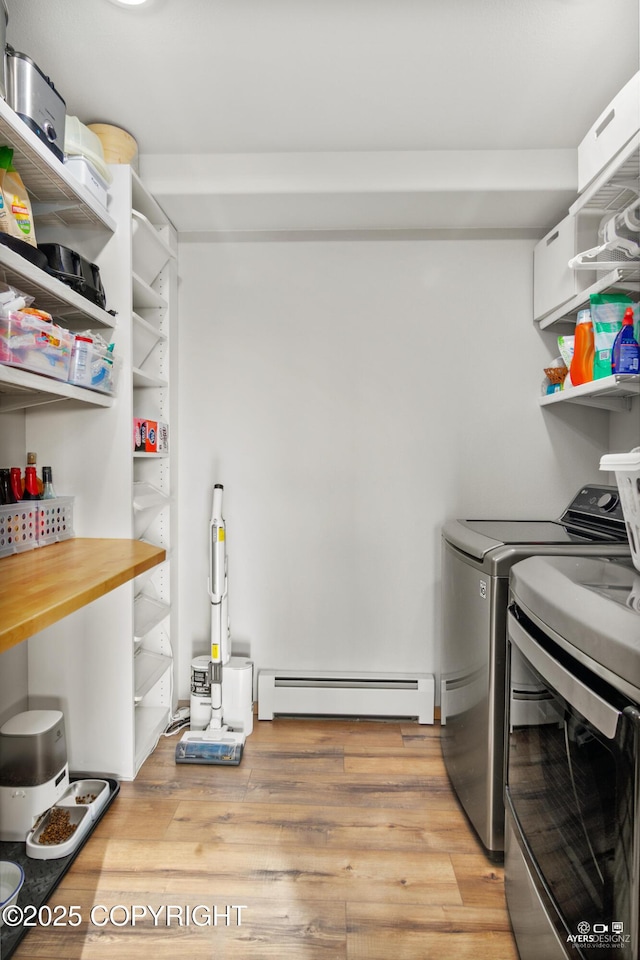 laundry area featuring washing machine and clothes dryer, baseboard heating, light wood finished floors, and laundry area