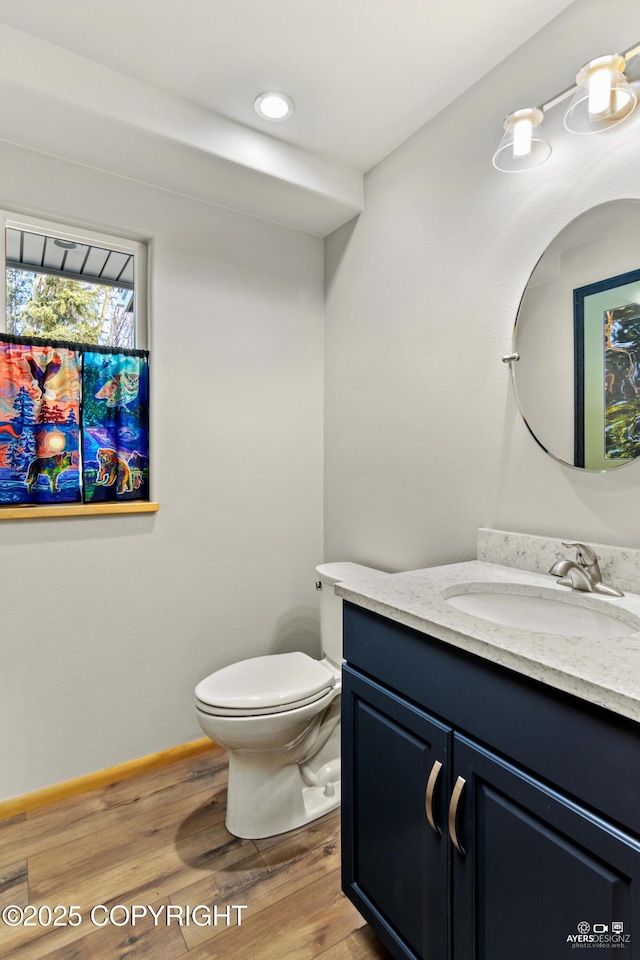 bathroom with toilet, vanity, baseboards, and wood finished floors