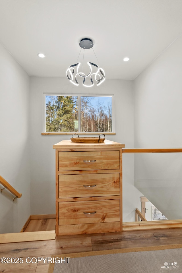 walk in closet with light wood finished floors and a chandelier