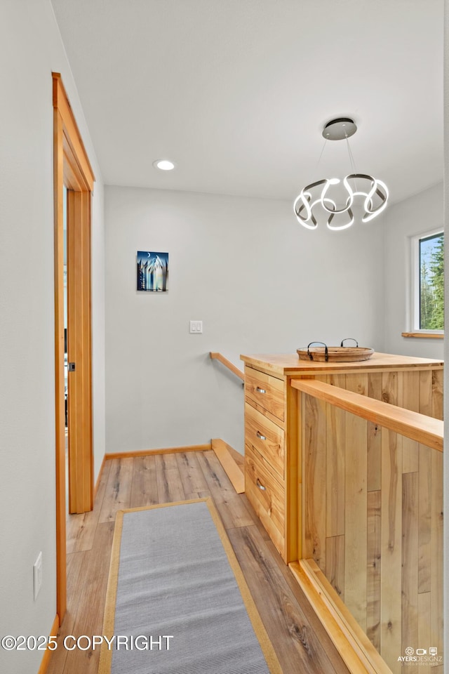 interior space featuring recessed lighting, light wood-style flooring, an inviting chandelier, and baseboards