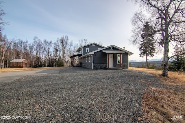 view of front of house with an outdoor structure, stone siding, and driveway