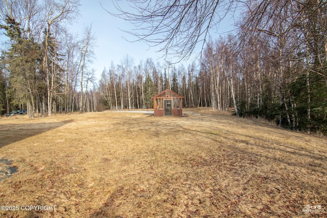 view of yard featuring a forest view and an outbuilding