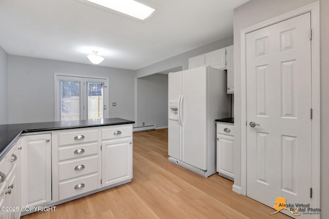 kitchen with a baseboard heating unit, dark countertops, and white refrigerator with ice dispenser