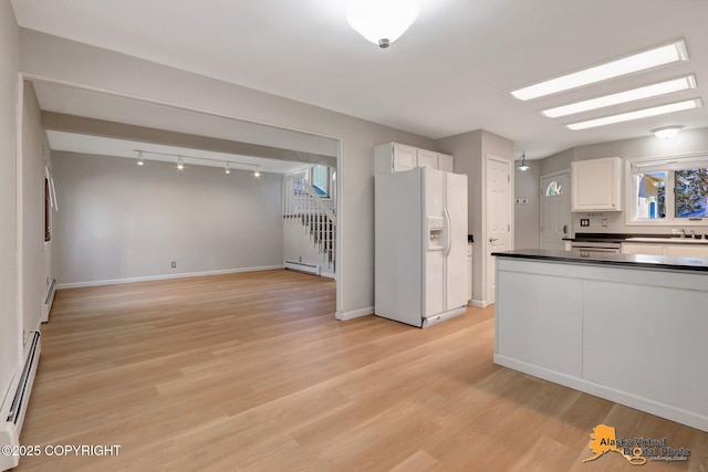 kitchen featuring dark countertops, baseboard heating, white cabinets, and white fridge with ice dispenser