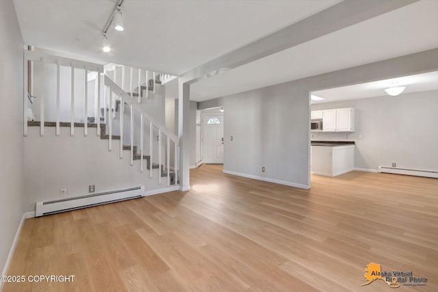 unfurnished living room featuring stairs, light wood finished floors, baseboards, and baseboard heating