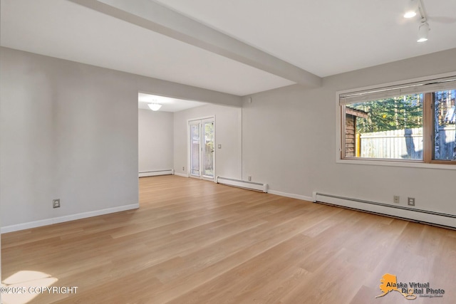 unfurnished room featuring a baseboard heating unit, light wood-style floors, and a wealth of natural light