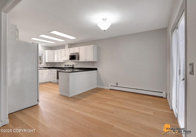 kitchen with dark countertops, light wood-type flooring, appliances with stainless steel finishes, a peninsula, and a baseboard radiator