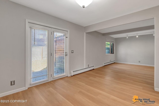 unfurnished room with baseboards, a baseboard heating unit, and light wood-style floors