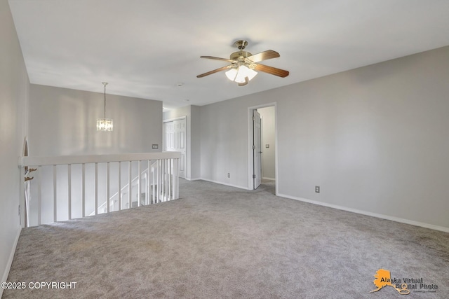 spare room with ceiling fan with notable chandelier, baseboards, and carpet floors