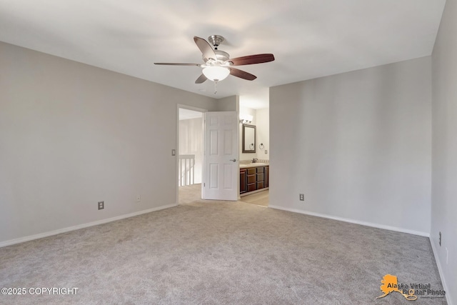 unfurnished bedroom featuring ceiling fan, baseboards, light carpet, and connected bathroom