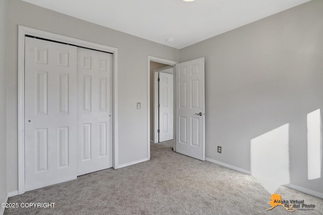 unfurnished bedroom with a closet, baseboards, and carpet