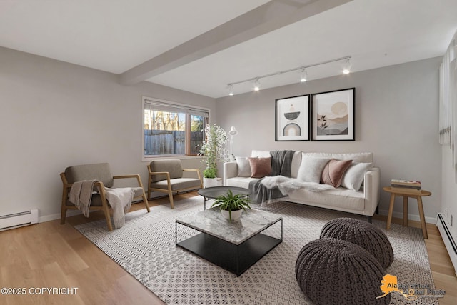 living area with baseboards, baseboard heating, beam ceiling, and light wood finished floors