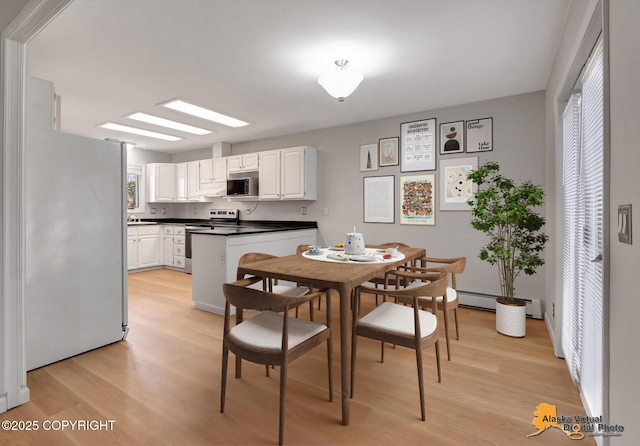 dining room featuring a baseboard heating unit and light wood-style flooring