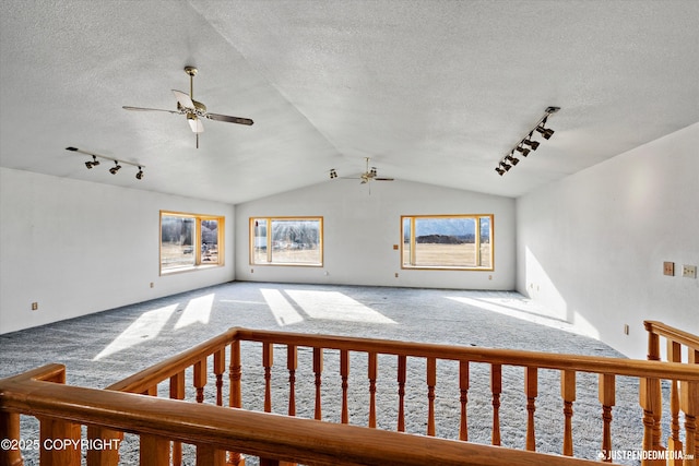 interior space featuring vaulted ceiling, a ceiling fan, carpet floors, and a textured ceiling