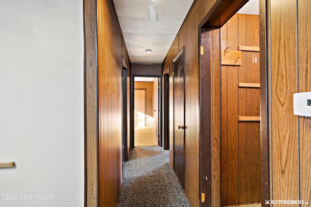 hallway with carpet and wood walls