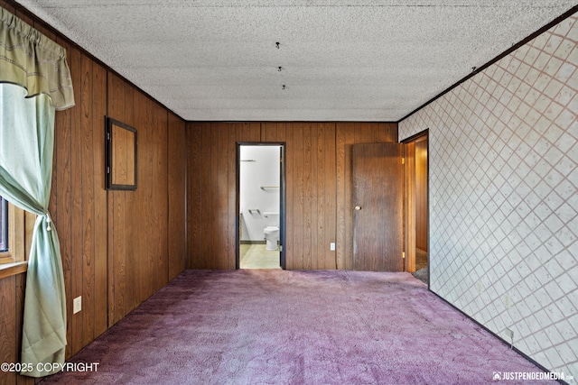 unfurnished bedroom featuring a textured ceiling, ensuite bath, carpet flooring, and crown molding