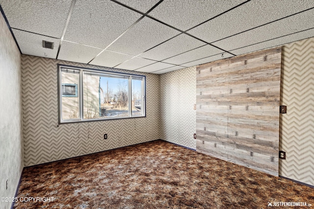 carpeted empty room with a paneled ceiling