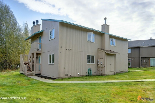 back of property featuring stairway, a lawn, and a chimney