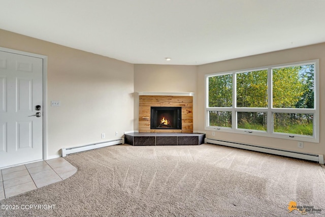 unfurnished living room with tile patterned flooring, a tiled fireplace, carpet, and baseboard heating