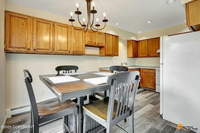 dining room featuring recessed lighting, a chandelier, baseboard heating, and wood finished floors