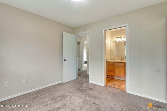 unfurnished bedroom featuring light carpet, ensuite bath, baseboards, and a sink