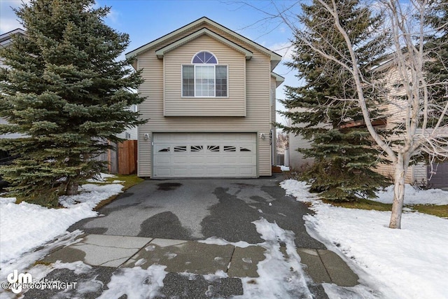 view of front of house with an attached garage, driveway, and fence