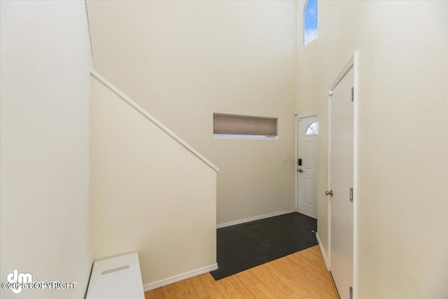 entrance foyer featuring baseboards, wood finished floors, and a towering ceiling