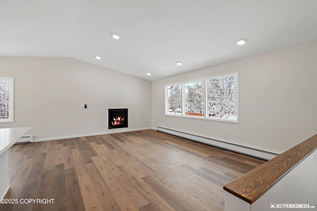 unfurnished living room featuring a baseboard heating unit, a warm lit fireplace, recessed lighting, wood-type flooring, and lofted ceiling