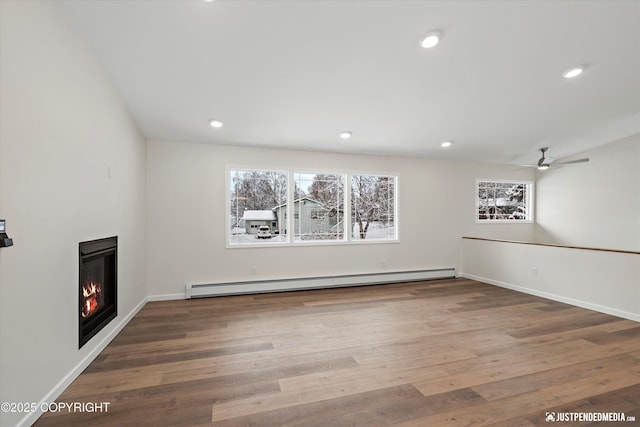 interior space with wood finished floors, a baseboard radiator, recessed lighting, ceiling fan, and a glass covered fireplace