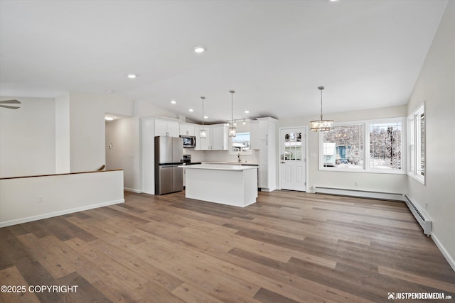 kitchen with a notable chandelier, wood finished floors, white cabinetry, stainless steel appliances, and vaulted ceiling