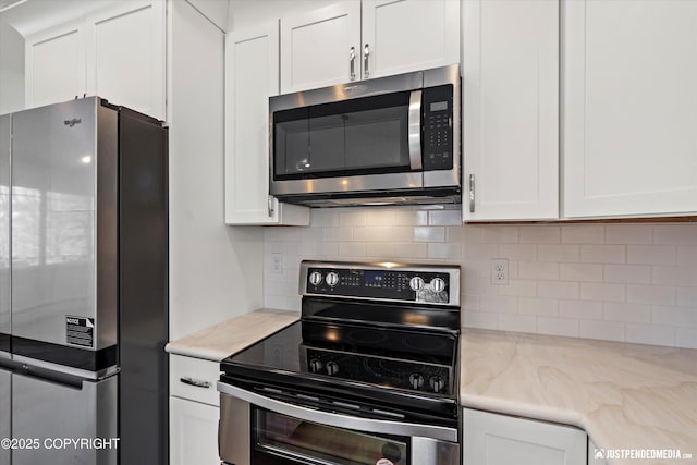 kitchen featuring light stone countertops, tasteful backsplash, appliances with stainless steel finishes, and white cabinetry