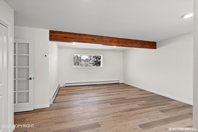 unfurnished room featuring beamed ceiling, wood finished floors, baseboards, and baseboard heating