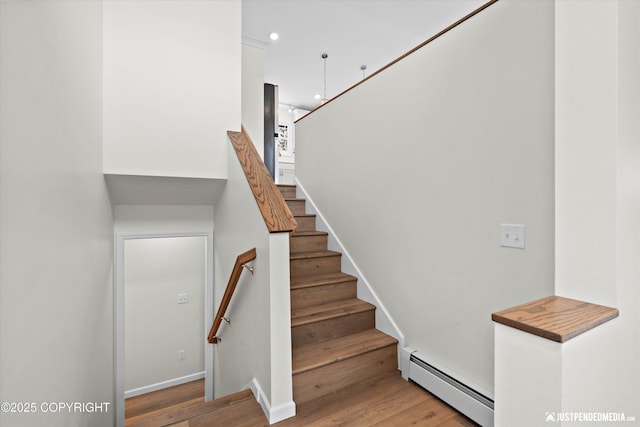 staircase featuring recessed lighting, a baseboard heating unit, baseboards, and wood finished floors