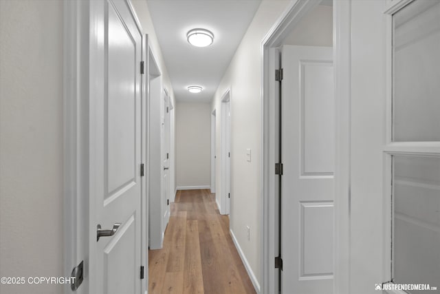 corridor with baseboards and light wood-style floors