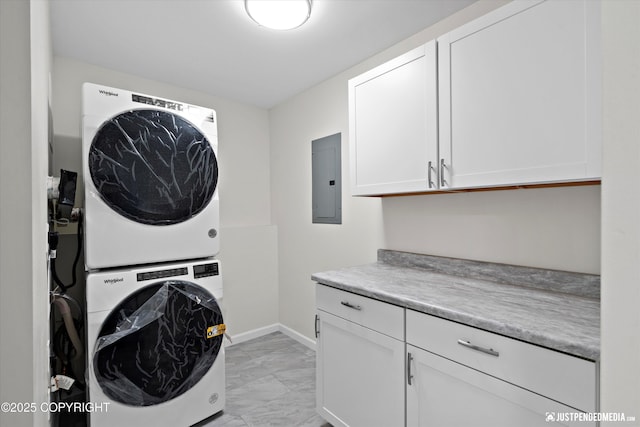 washroom with marble finish floor, electric panel, stacked washing maching and dryer, cabinet space, and baseboards