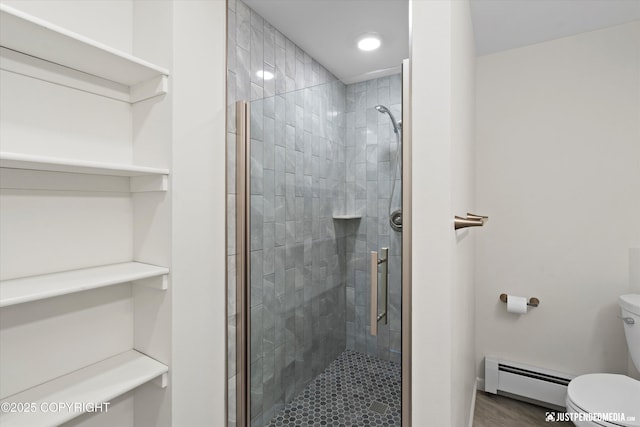 bathroom featuring a stall shower, toilet, and a baseboard heating unit