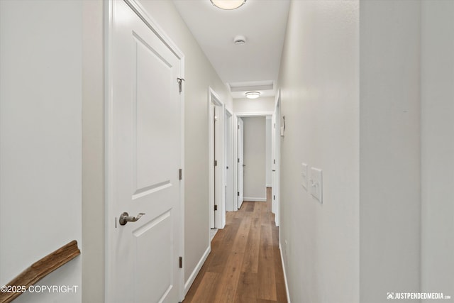 hallway featuring baseboards and wood finished floors