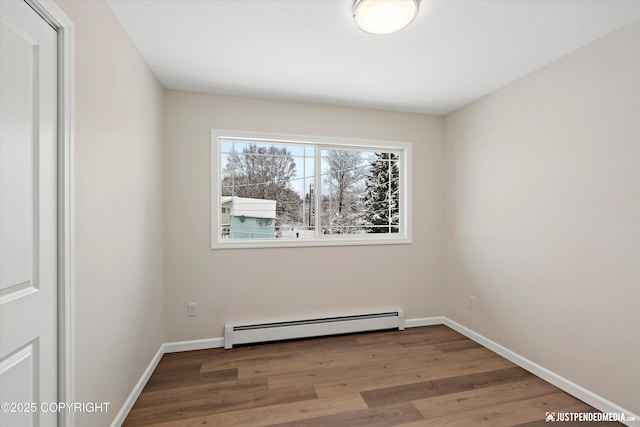 spare room with wood finished floors, baseboards, and baseboard heating