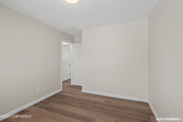 spare room with baseboards and wood finished floors