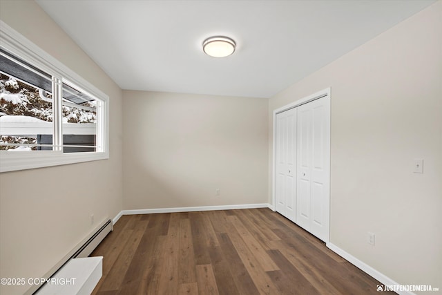 unfurnished bedroom with wood finished floors, baseboards, a closet, and a baseboard radiator