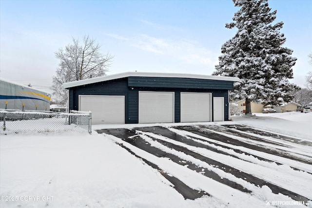 snow covered garage with a garage and fence