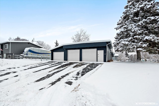 snow covered garage featuring a detached garage