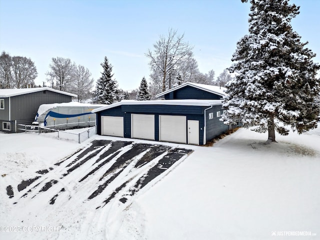 snow covered garage with a garage and fence