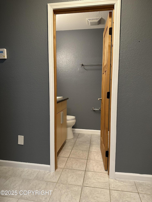 bathroom with vanity, visible vents, baseboards, tile patterned floors, and toilet