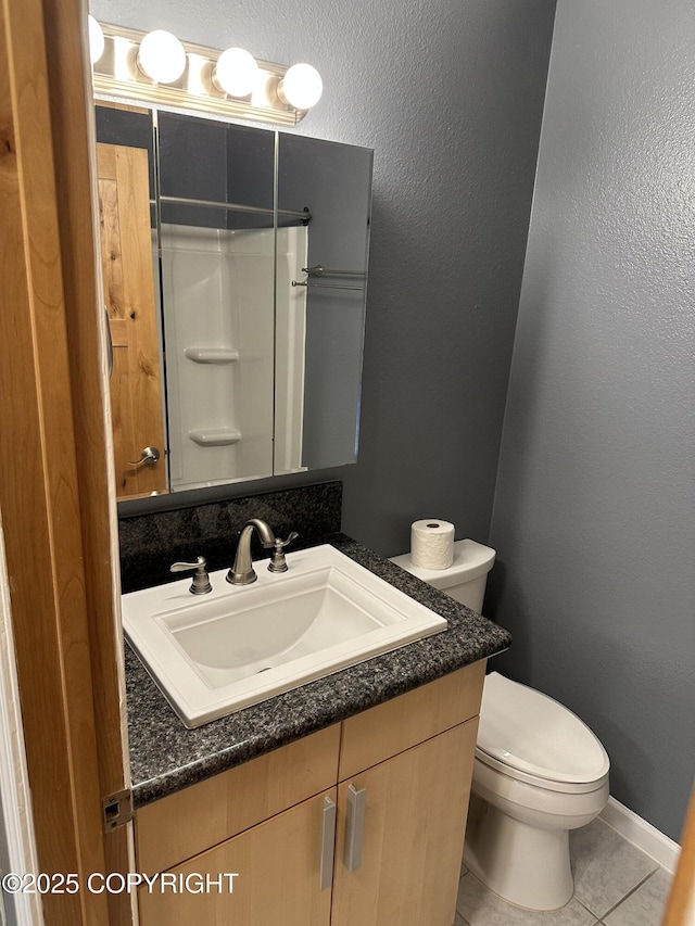 full bathroom featuring tile patterned flooring, walk in shower, toilet, a textured wall, and vanity